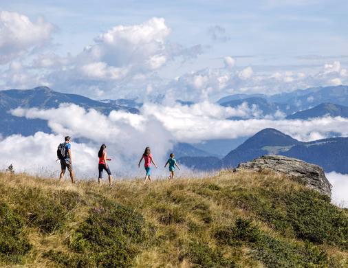 Familie wandert auf einem Bergkamm im Zillertal über einem Wolkenmeer mit Gipfelblick